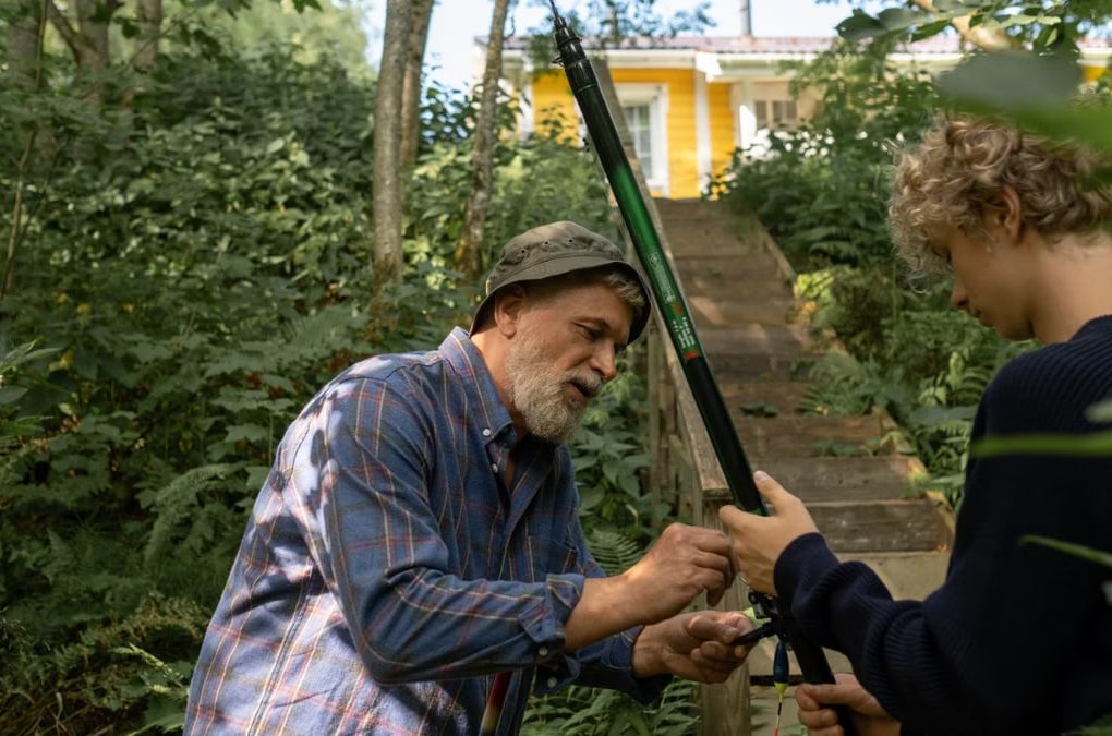 Grandfather and grandson preparing fishing rods outdoors, enjoying quality family time in nature.