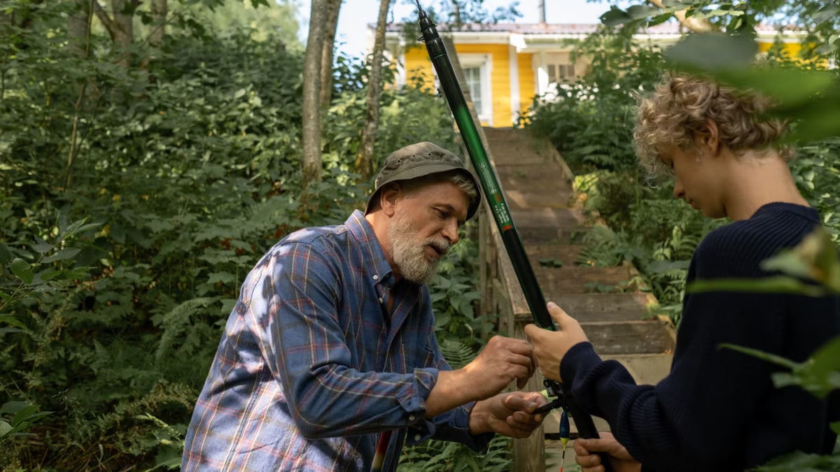 Grandfather and grandson preparing fishing rods outdoors, enjoying quality family time in nature.
